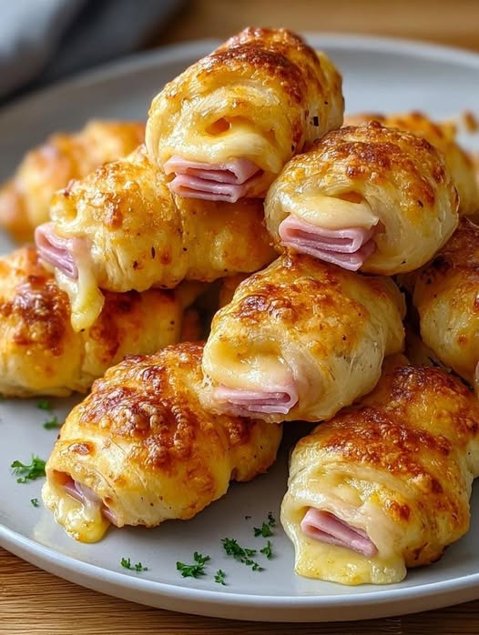 Ces feuilletés jambon – fromage sont irrésistibles : délicieusement croustillants à l’extérieur et fondants à l’intérieur. Parfaits en apéritif, en en-cas , en entrée ou même au petit-déjeuner. Rapides à préparer, ils font toujours l’unanimité.  Ingrédients 1 rouleau de pâte feuilletée fraîche  150 g de jambon cuit (tranché)  150-200 g de kaas (emmental, gouda de mozzarella)  1 œuf (battu, pour dorer)  Poivre noir (facultatif)  Origan ou thym séchés (facultatif)  Méthode de préparation :